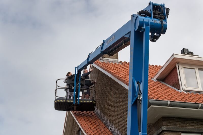 schilder in de duinkerksetraat op hoogwerker